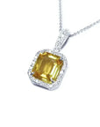 6.01 ct. emerald cut yellow sapphire pendant with diamond halo in 18K white gold.
