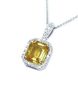 6.01 ct. emerald cut yellow sapphire pendant with diamond halo in 18K white gold.