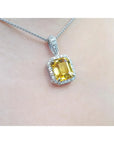 Yellow sapphire gemstone pendant on a chain against a neutral background