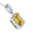 Emerald cut 6.01 ct. yellow sapphire pendant with diamond halo in 18K white gold.