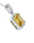 Emerald cut 6.01 ct. yellow sapphire pendant with diamond halo in 18K white gold.