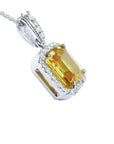 Emerald cut 6.01 ct. yellow sapphire pendant with diamond halo in 18K white gold.