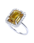 Emerald cut yellow sapphire ring with diamond halo in 14K white gold.