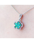 14K white gold emerald cluster necklace with diamond halo, clover-like five-petal design.
