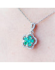 14K white gold emerald cluster necklace with diamond halo, clover-like five-petal design.