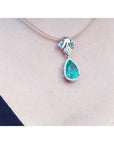 18K white gold enhancer necklace with a pear-shaped emerald and halo diamonds on a thin choker.