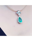 18K white gold enhancer necklace with a pear-shaped emerald and halo diamonds on a thin choker.