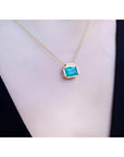 Natural Muzo Colombian emerald solitaire necklace in 18K yellow gold, east-west orientation.