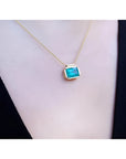 Natural Muzo Colombian emerald solitaire necklace in 18K yellow gold, east-west orientation.