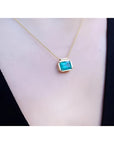 Natural Muzo Colombian emerald solitaire necklace in 18K yellow gold, east-west orientation.