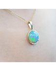 Opal pendant necklace on a plain skin background.
