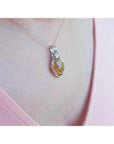 Opal pendant necklace on a person's neck wearing a pink top.