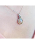 Welo Ethiopian multicolor opal pendant with silver wire wrap, worn on a pink top.