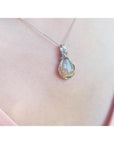 Welo Ethiopian multicolor opal pendant with silver wire wrap, worn on a pink top.