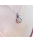 Welo Ethiopian multicolor opal pendant with silver wire wrap, worn on a pink top.