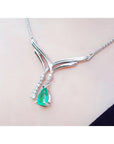 14K white gold necklace with a pear-shaped emerald pendant and diamond accents on a chevron design.