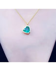Tilted heart emerald necklace with halo diamonds on an 18K yellow gold chain.