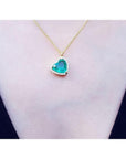 Tilted heart emerald necklace with halo diamonds on an 18K yellow gold chain.