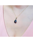 Welo black opal teardrop pendant with red-orange and blue-green flashes on a 14K yellow gold chain.
