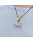 Necklace with an opal pendant on a person's neck and light blue background.