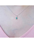 0.27 ct emerald necklace pendant in 14K white gold, worn on a woman's chest.