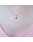 0.27 ct emerald necklace pendant in 14K white gold, worn on a woman's chest.