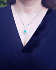 woman wearing a blue top with a emerald necklace featuring a green pendant in white gold