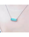 18K white gold necklace with a rectangular emerald-cut Colombian emerald and diamond halo, East-West design.