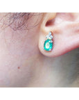 Close-up of an ear wearing a natural colombian emerald earring with a white background