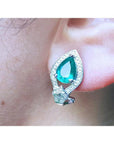 Close-up of a teardrop emerald earring clip-on system on an ear.