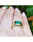 1.53 ct. square emerald bezel set in an 18K yellow gold solitaire ring on a hand.