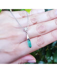 Colombian emerald briolette necklace with a diamond slider on 14K white gold chain, held by a hand.