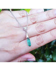 Colombian emerald briolette necklace with a diamond slider on 14K white gold chain, held by a hand.