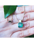 Displaying a natural Asscher cut natural emerald pendant necklace on a woman's han