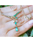 14K yellow gold necklace with marquise and pear-shaped Colombian emeralds and diamonds on a hand.