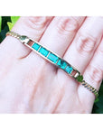 14K yellow gold bracelet with five emerald-cut Colombian emeralds on a woman's hand.