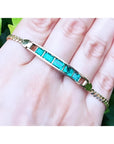 14K yellow gold bracelet with five emerald-cut Colombian emeralds on a woman's hand.