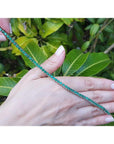Natural Colombian emerald tennis bracelet, round cut, prong set in 14K gold, held by hands.