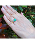 18k yellow gold ring with a GIA emerald and two trillion side diamonds on a hand.