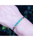 2.40 ct emerald and diamond 14K yellow gold bracelet on a wrist, featuring vibrant bluish-green stones.