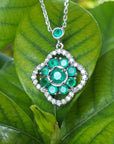 Green gemstones cluster of natural emeralds necklace with white gold chain on green leaves