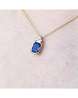14k gold necklace with a rectangular blue sapphire pendant and three accent diamonds.