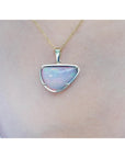 Opal pendant necklace on a person's neck with a plain background