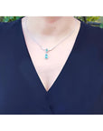 Pear shaped emerald and diamond necklace in 14K white gold on a woman's neck.