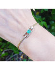 14K yellow gold bracelet with a central emerald-cut Colombian emerald flanked by diamond rows.