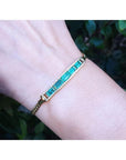 2.40 ct. Colombian emerald and diamond 14K yellow gold bracelet on a wrist.