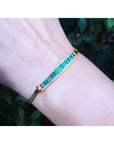 2.40 ct. Colombian emerald and diamond 14K yellow gold bracelet on a wrist.