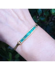 2.40 ct. Colombian emerald and diamond 14K yellow gold bracelet on a wrist.