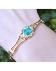 14K yellow gold women's bracelet with a central oval-cut natural emerald and sparkling accents.