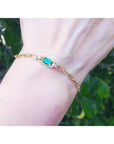 14K yellow gold paper clip bracelet with a rectangular natural emerald and diamond accents on a wrist.
